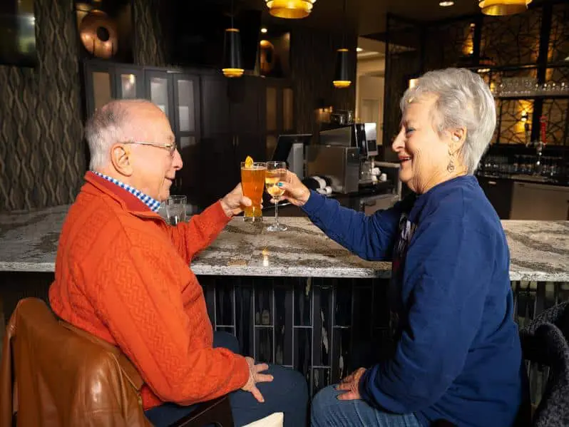 Two residents cheersing drinks at the bar