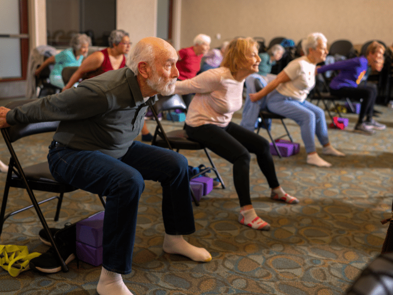 A group of residents doing yoga in chairs