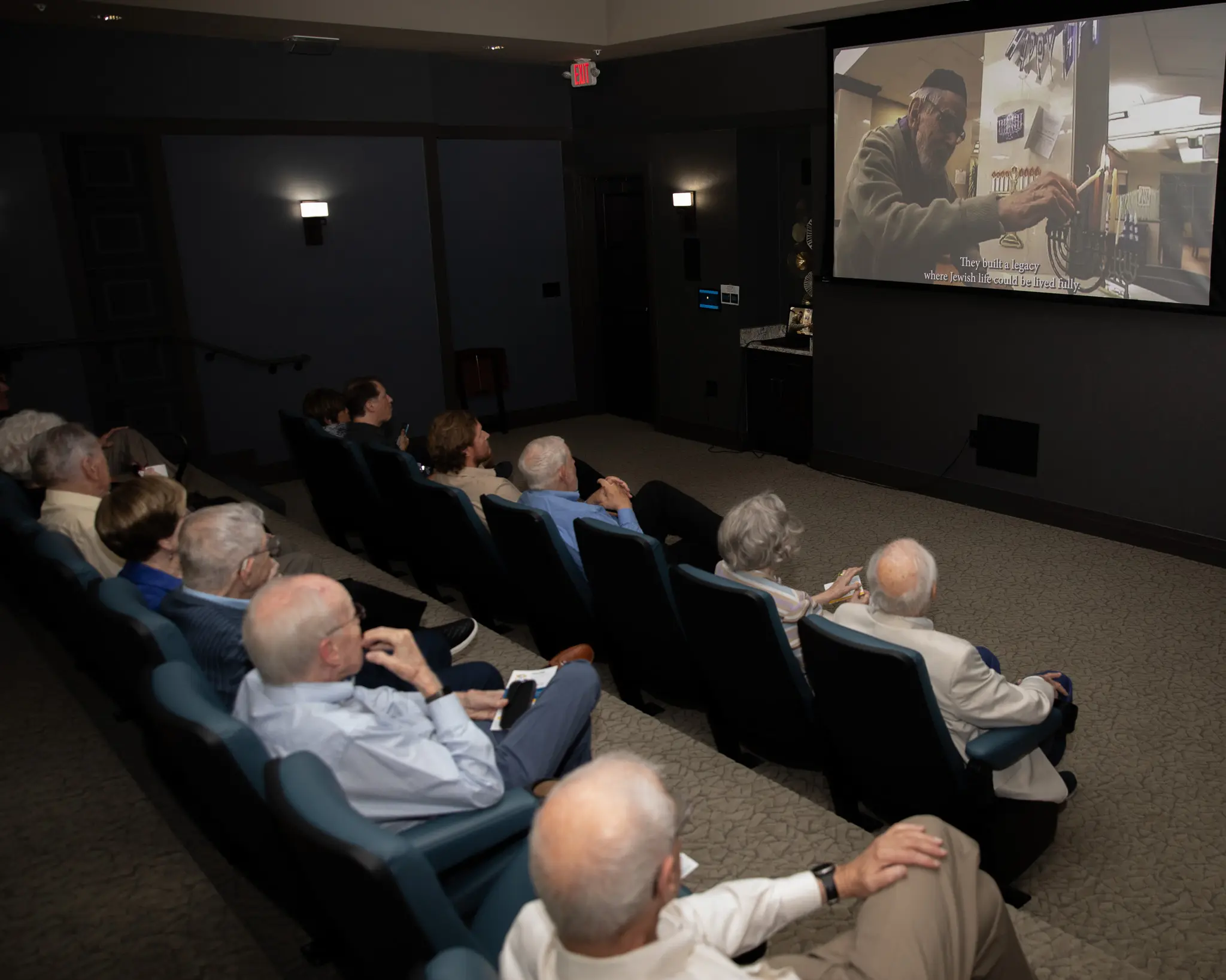 People sitting in a theatre watching a video