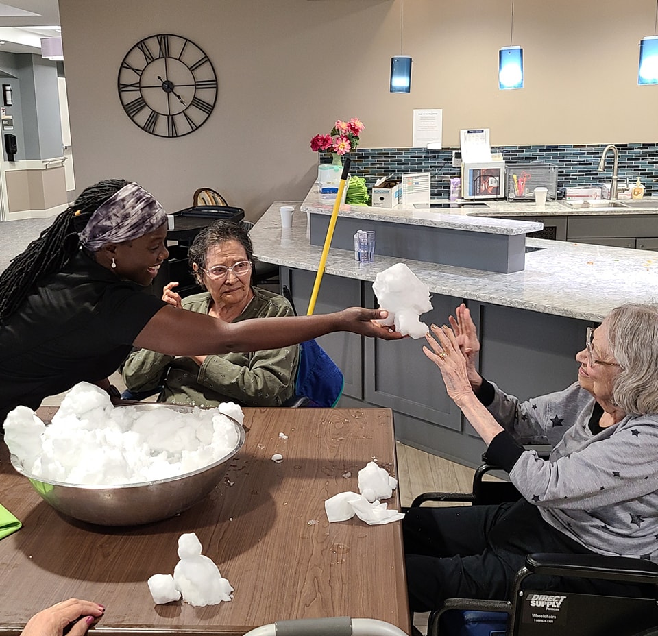 Lynette and Memory Support residents playing with snow indoors.