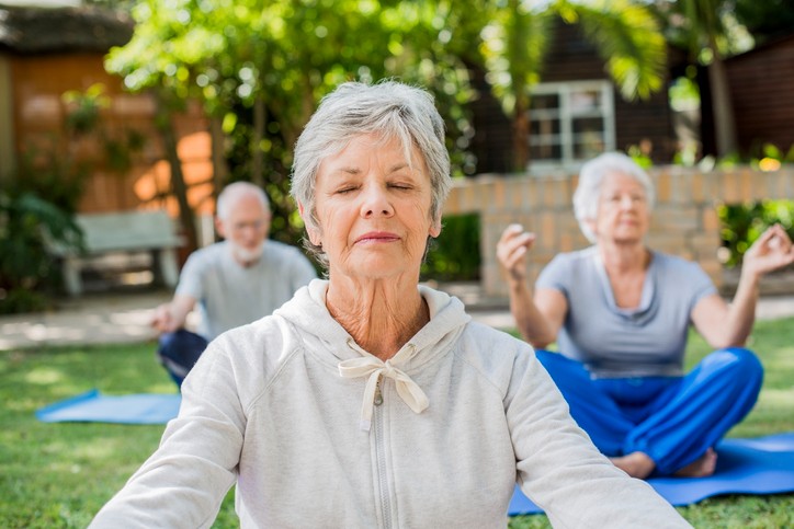 Senior living residents doing yoga outdoors